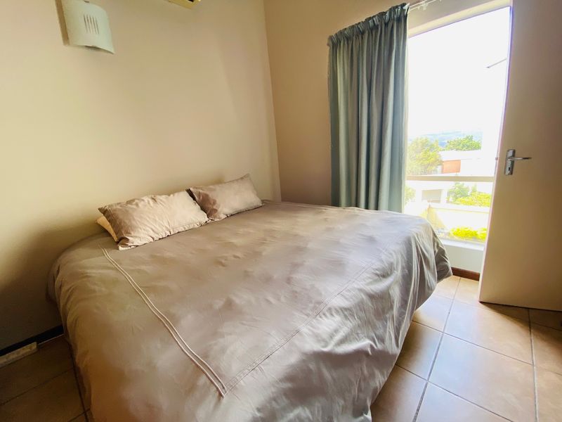A bedroom featuring tiled flooring, a wall-mounted light fixture, and a sliding glass door providing natural light and access to an outdoor area.
