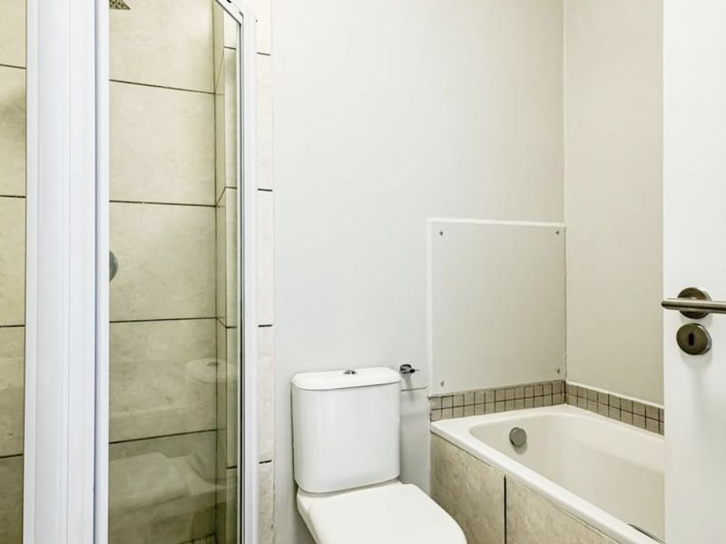 A clean, functional bathroom featuring a separate shower enclosure, a bathtub with tiled splashback, and a standard toilet.