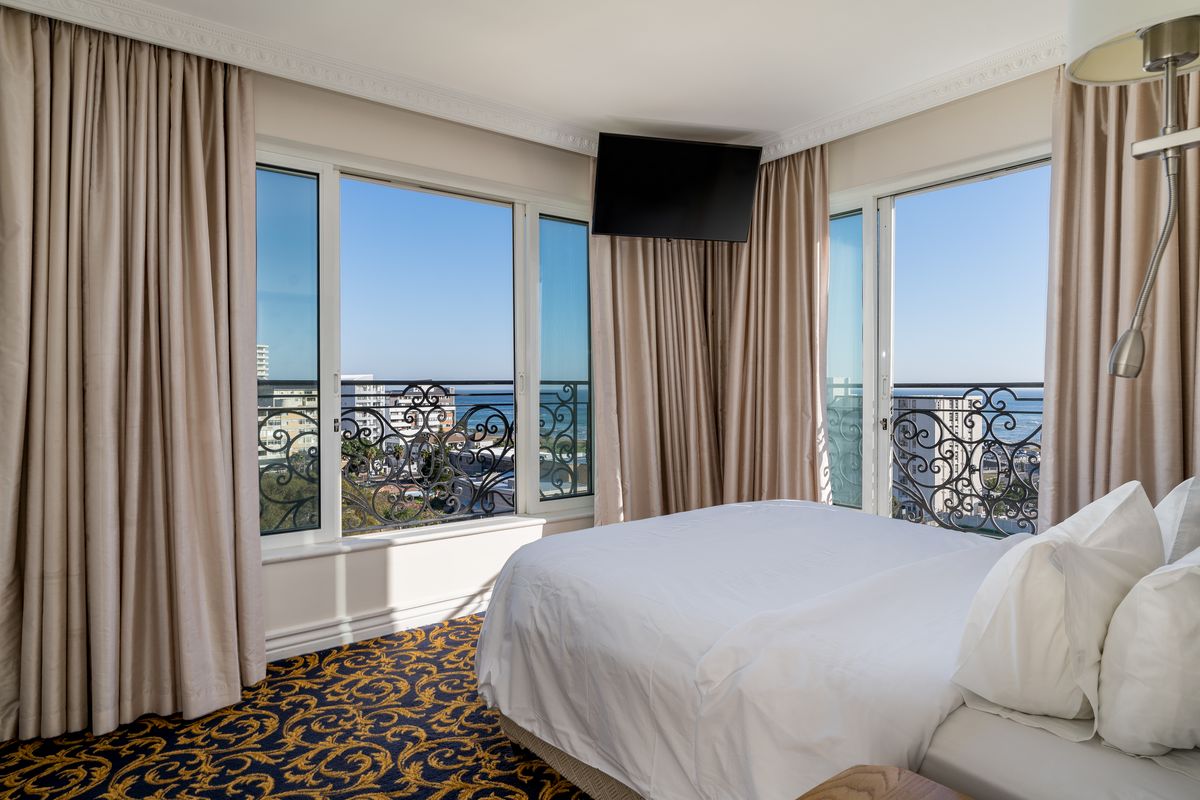 A well-maintained bedroom featuring large windows with decorative wrought iron railings, offering scenic coastal views and abundant natural light.