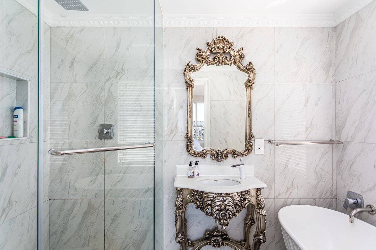 Modern bathroom featuring marble-look wall tiles, a glass-enclosed shower with a rainfall showerhead, and a freestanding bathtub.