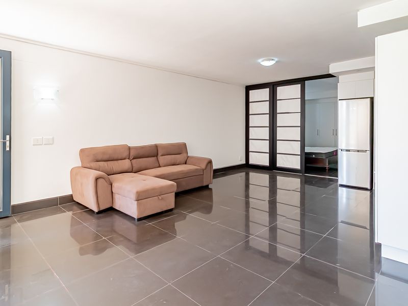 Spacious open-plan living area featuring polished dark floor tiles, modern sliding room dividers, and integrated storage cabinetry.
