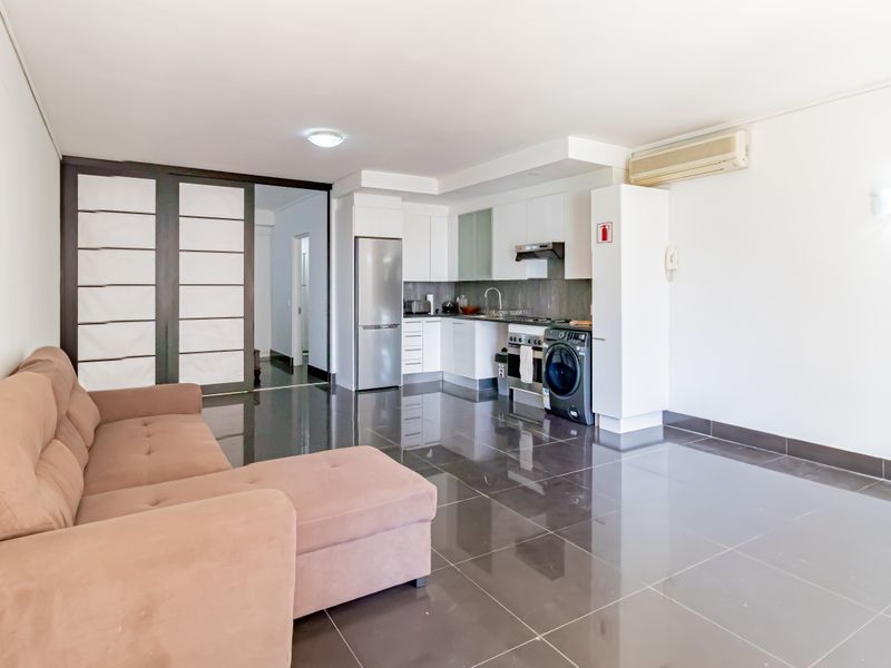 Open-plan living area featuring a modern kitchen with built-in cabinetry, gas hob, and sleek tiled flooring, seamlessly connected to the lounge space.