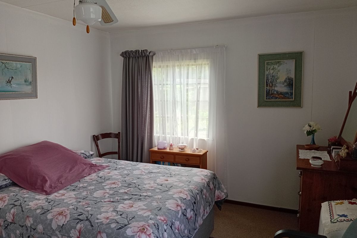 A functional bedroom featuring a ceiling fan and neutral wall finishes, offering a comfortable space with natural light.