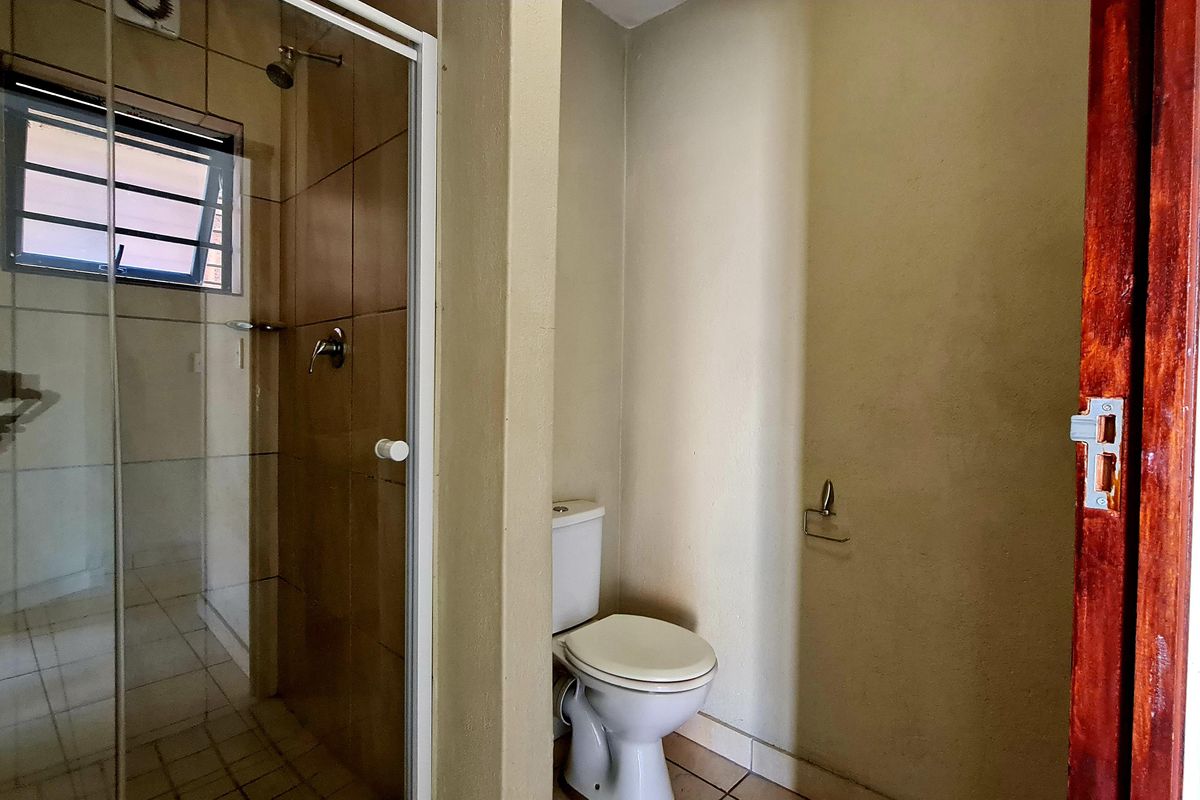 A functional bathroom featuring a tiled shower enclosure and a separate toilet area with neutral wall finishes.
