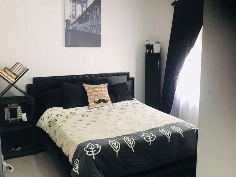 A bedroom featuring tiled flooring and a window with a curtain rod, providing a functional and neutral space.