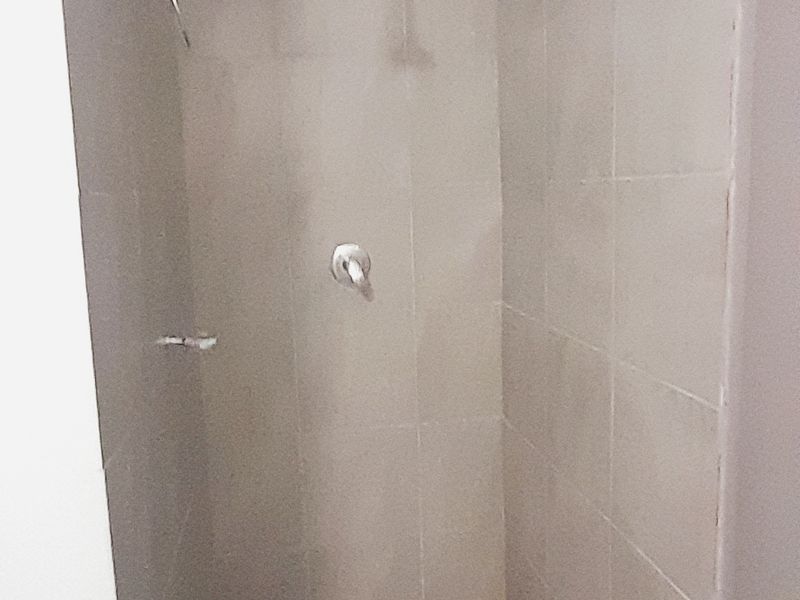 A functional laundry area featuring tiled flooring, a tiled splashback, and dedicated plumbing connections for laundry appliances.