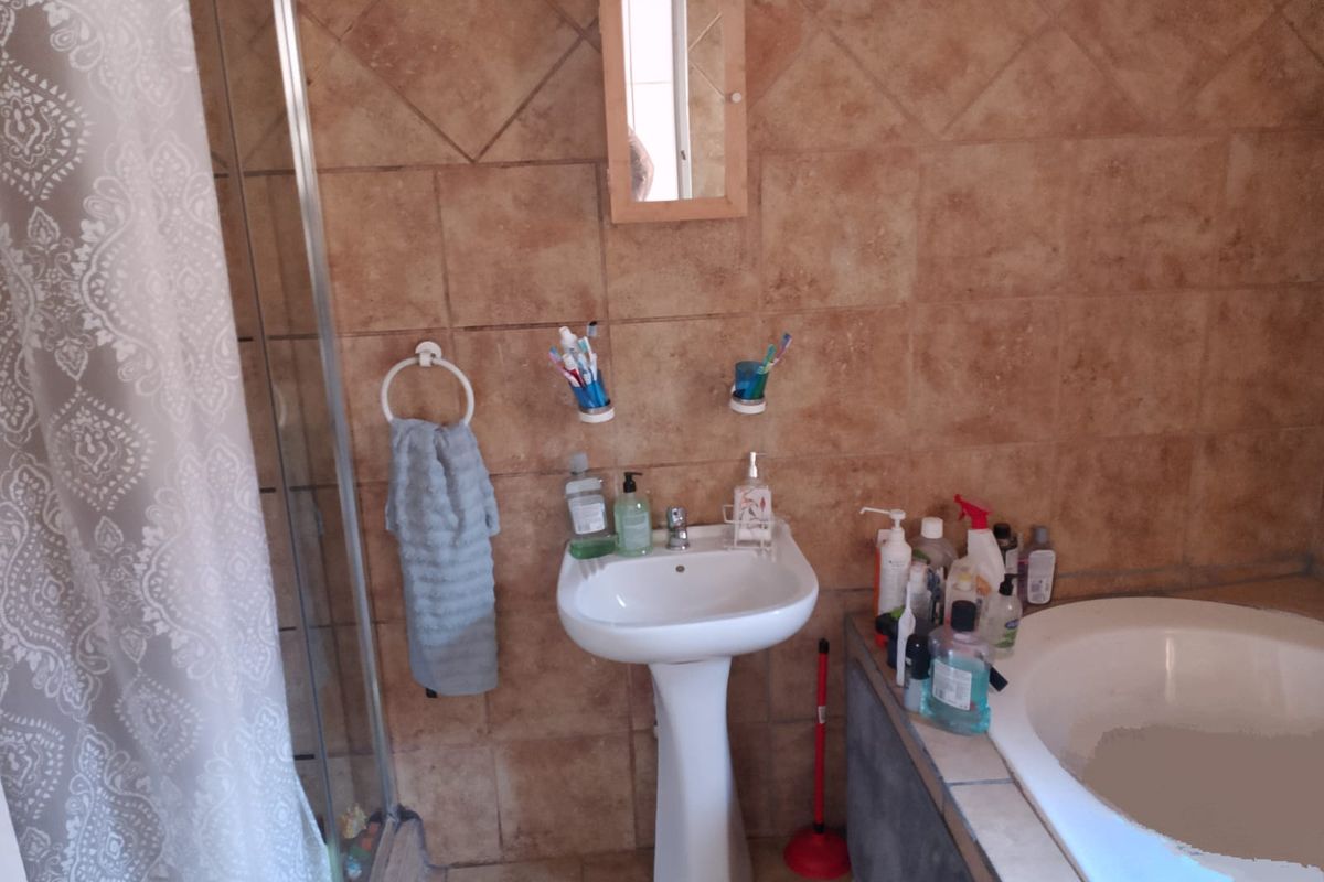 Bathroom featuring a pedestal sink, a built-in bathtub, and a separate shower enclosure with tiled walls.