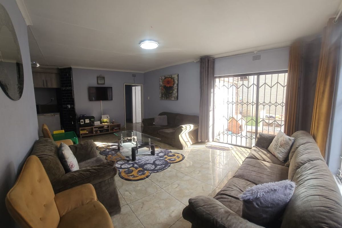 Spacious living room featuring tiled flooring, large sliding glass doors with security gates, and direct access to the outdoor area.
