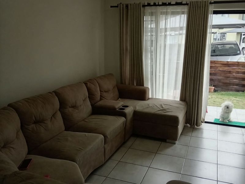 A living room featuring tiled flooring and a sliding glass door providing access to the outdoor area.