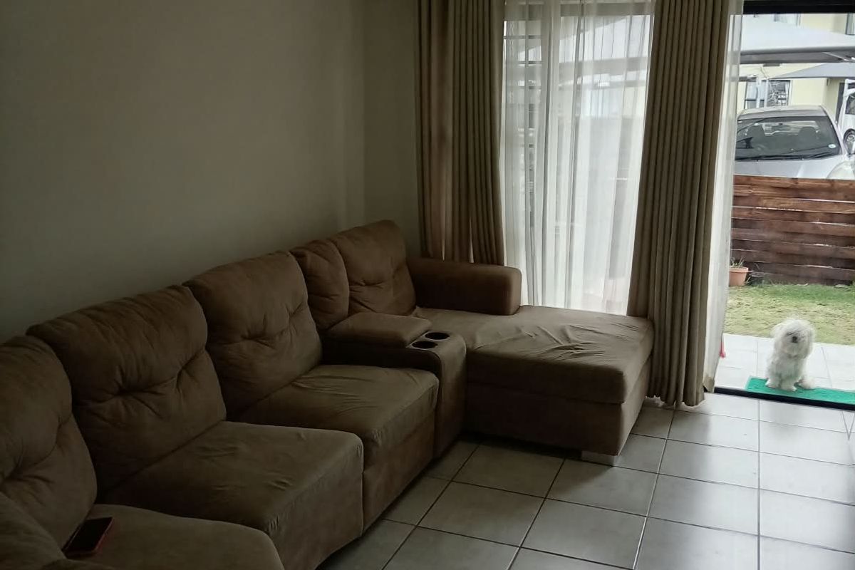 A living room featuring tiled flooring and a sliding glass door providing access to the outdoor area.
