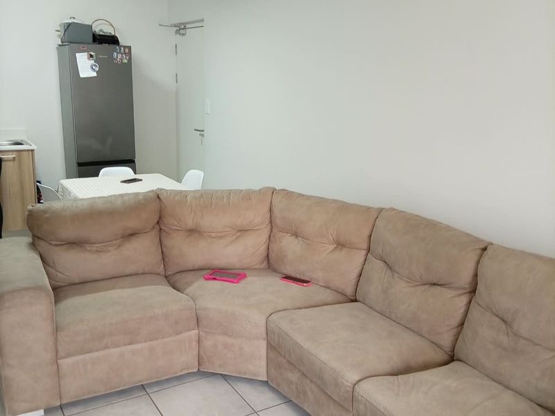 Open plan living area featuring neutral tiled flooring and a compact kitchen corner, providing a functional and versatile space for daily living.