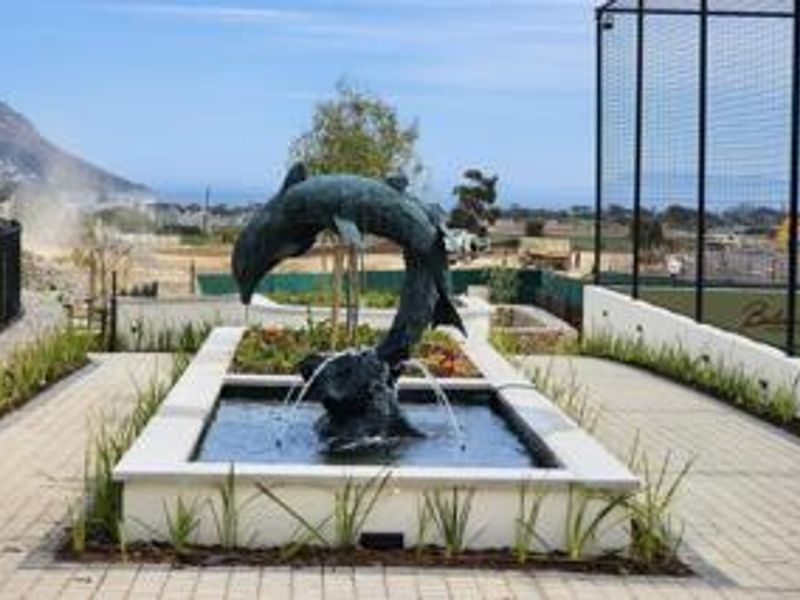 A well-maintained outdoor communal area featuring a decorative dolphin water fountain, paved pathways, and landscaped garden beds.