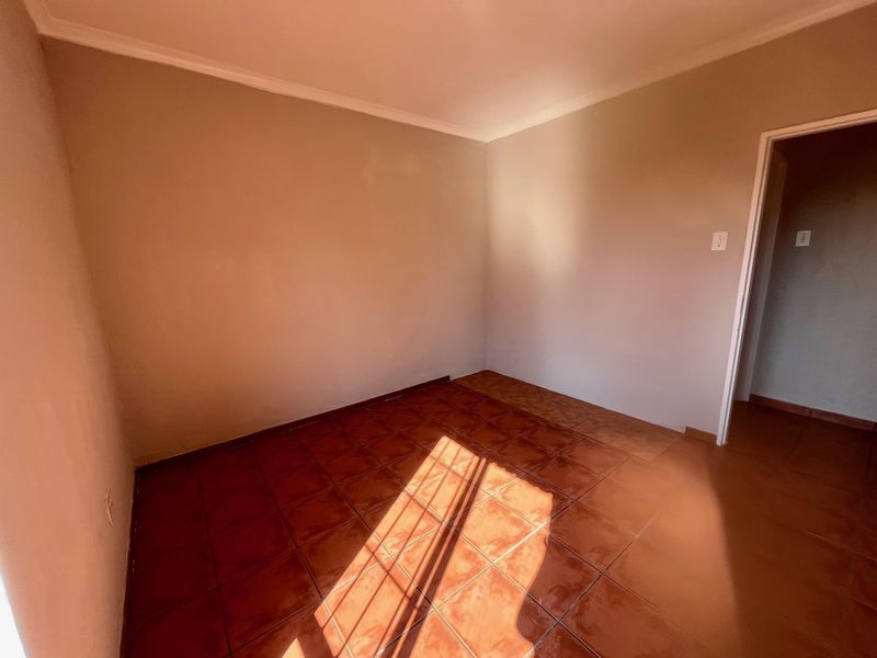 A vacant bedroom featuring neutral wall paint and terracotta-style ceramic floor tiles, offering a clean and versatile space ready for personalization.