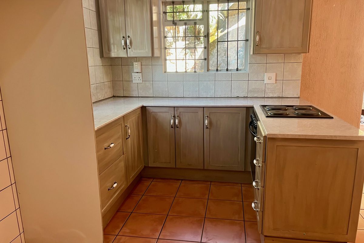 A functional kitchen featuring built-in cabinetry, laminate countertops, ceramic tile backsplash, and an integrated electric hob and oven.