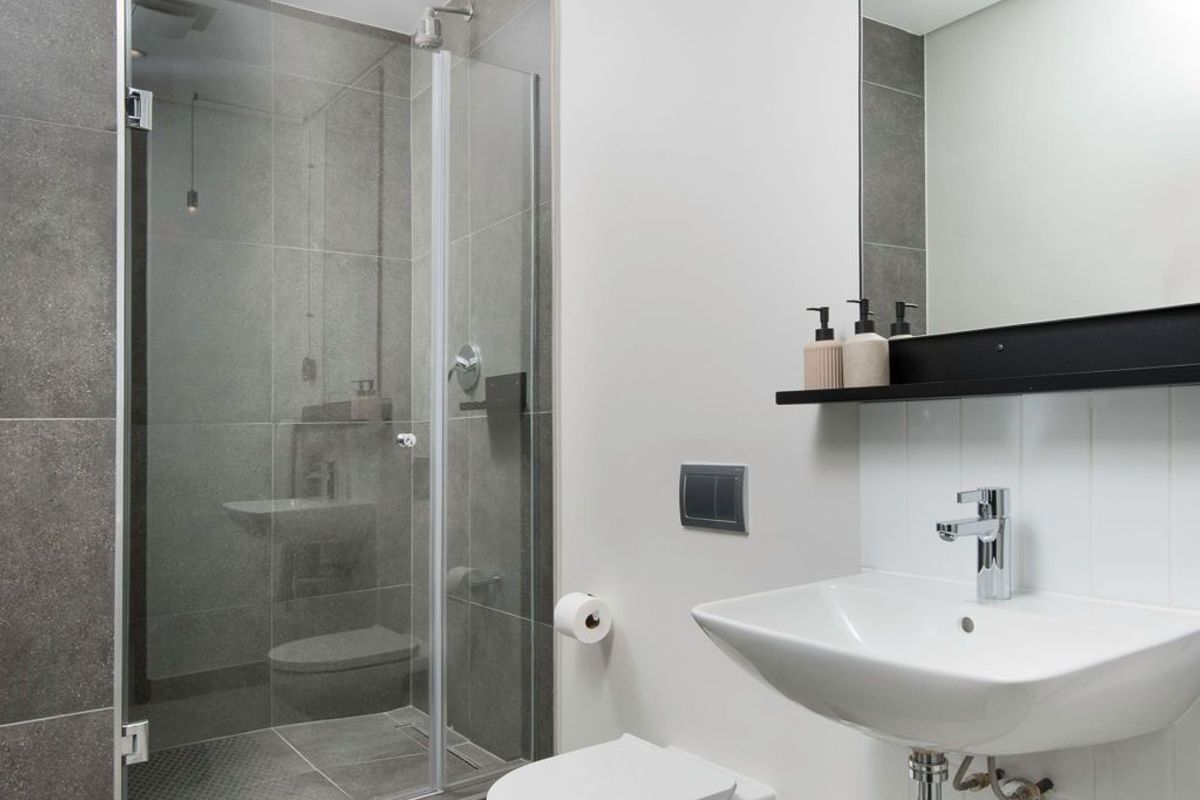 Modern bathroom featuring a glass-enclosed walk-in shower, wall-mounted toilet, and a sleek wall-hung basin with a large mirror.