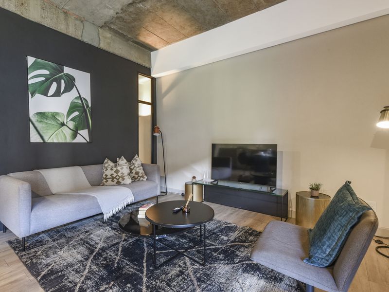 Modern living room featuring an industrial-style exposed concrete ceiling and light-toned laminate flooring, creating a contemporary and stylish atmosphere.