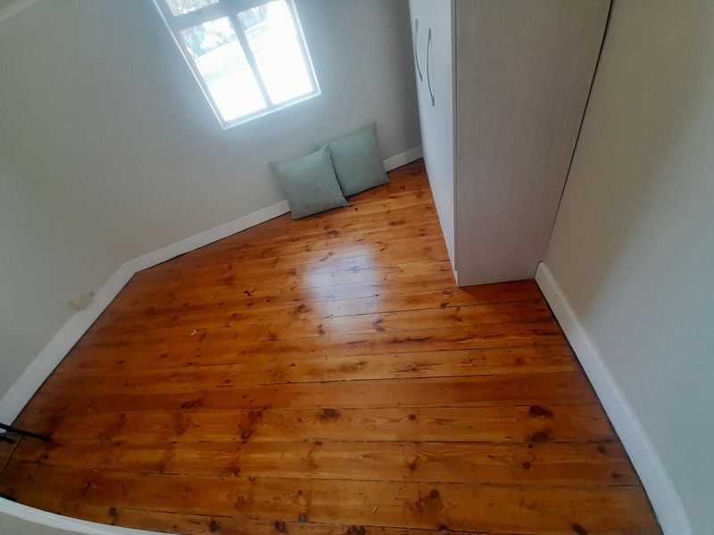 A bedroom featuring polished timber flooring and a built-in wardrobe, offering a clean and functional space.