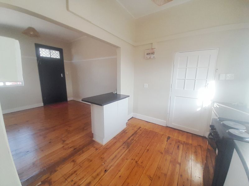 Open plan living and kitchen area featuring original hardwood flooring, a central kitchen island, and direct access to exterior doors.