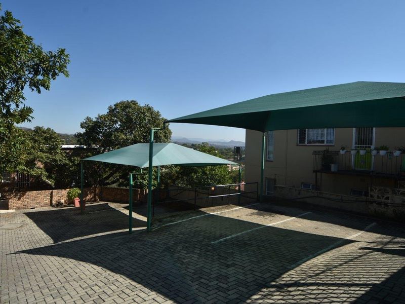 Exterior view of the apartment complex parking area featuring paved driveway space and installed shade cloth carports.