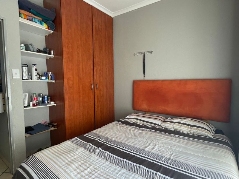 A bedroom featuring a built-in wooden wardrobe and integrated shelving unit, providing functional storage space.