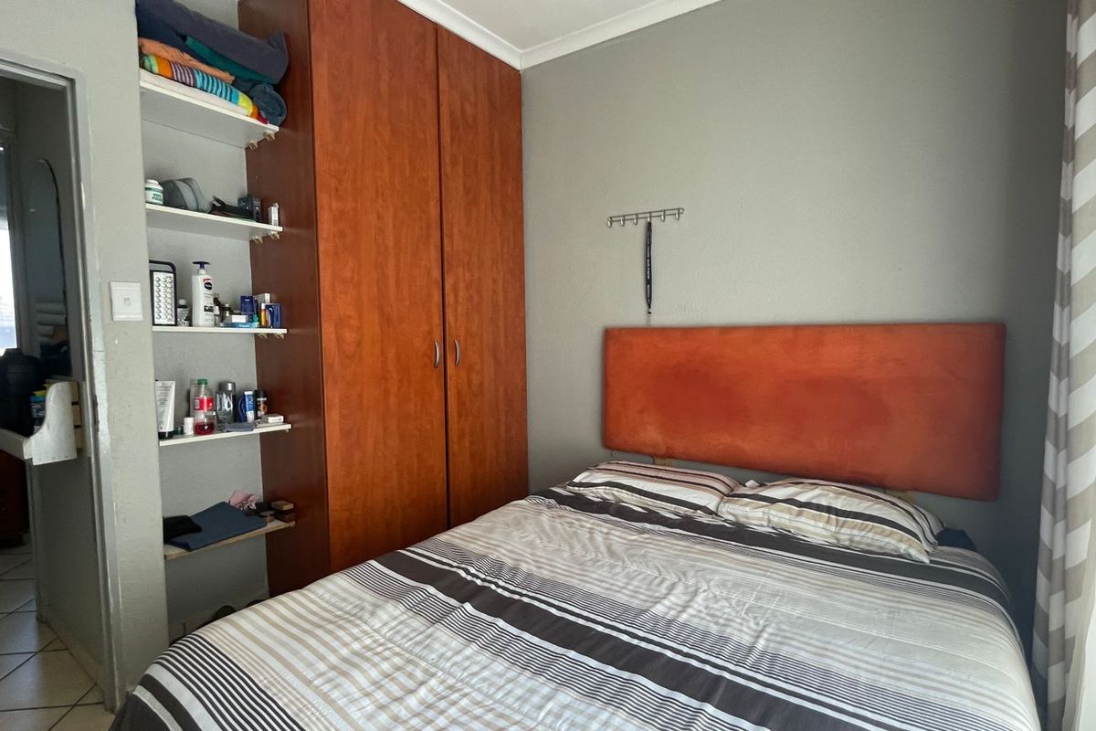 A bedroom featuring a built-in wooden wardrobe and integrated shelving unit, providing functional storage space.