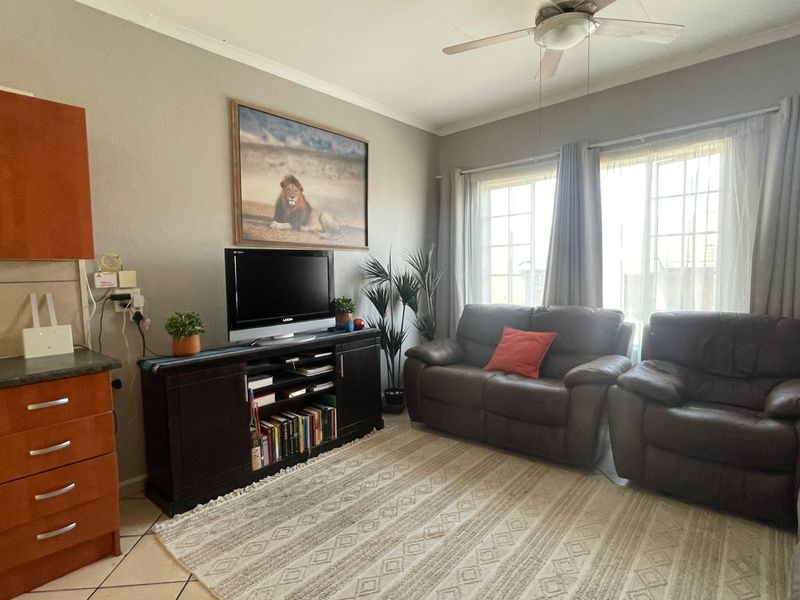 Open-plan living area featuring a compact kitchen with built-in cabinetry, gas hob, and oven, flowing into a comfortable lounge space with natural light.