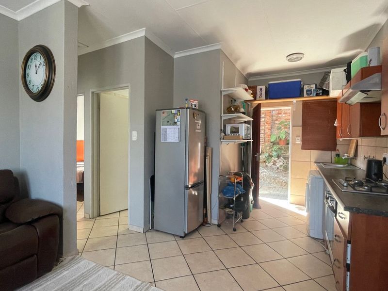 Open-plan living area featuring a functional kitchen with built-in cabinetry, gas hob, and tiled flooring, providing direct access to an outdoor space.
