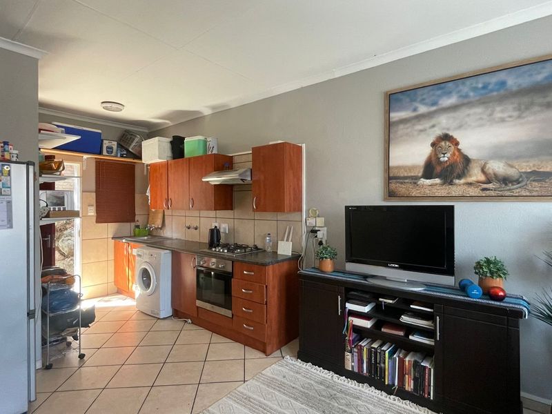 Open-plan living area featuring a functional kitchen with built-in cabinetry, gas hob, oven, and tiled flooring, seamlessly integrated with the living space.