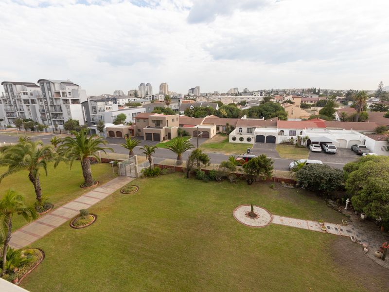 Elevated view overlooking a well-maintained communal garden with paved pathways and surrounding residential neighbourhood.