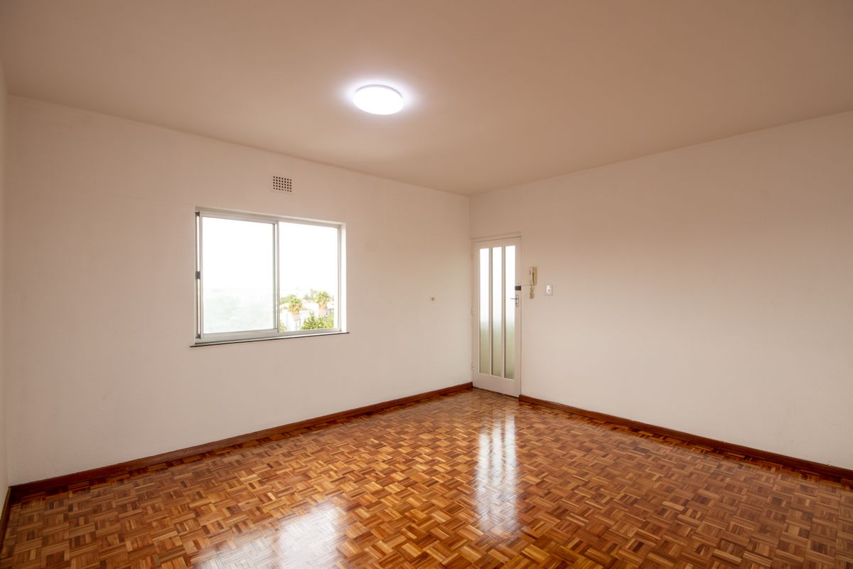 An empty bedroom featuring well-maintained parquet flooring, a sliding window, and an integrated intercom system.