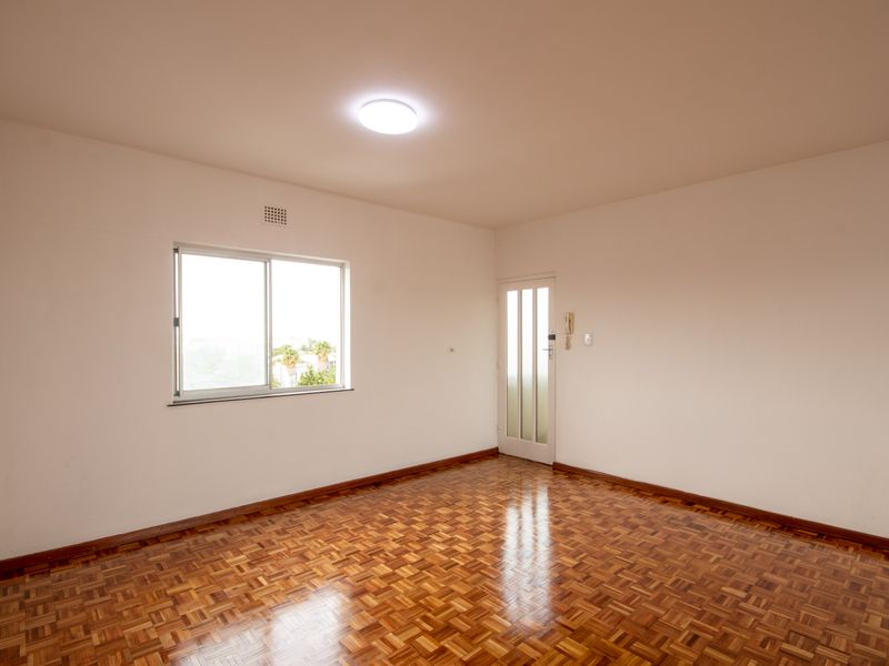 An empty bedroom featuring well-maintained parquet flooring, a sliding window, and an integrated intercom system.