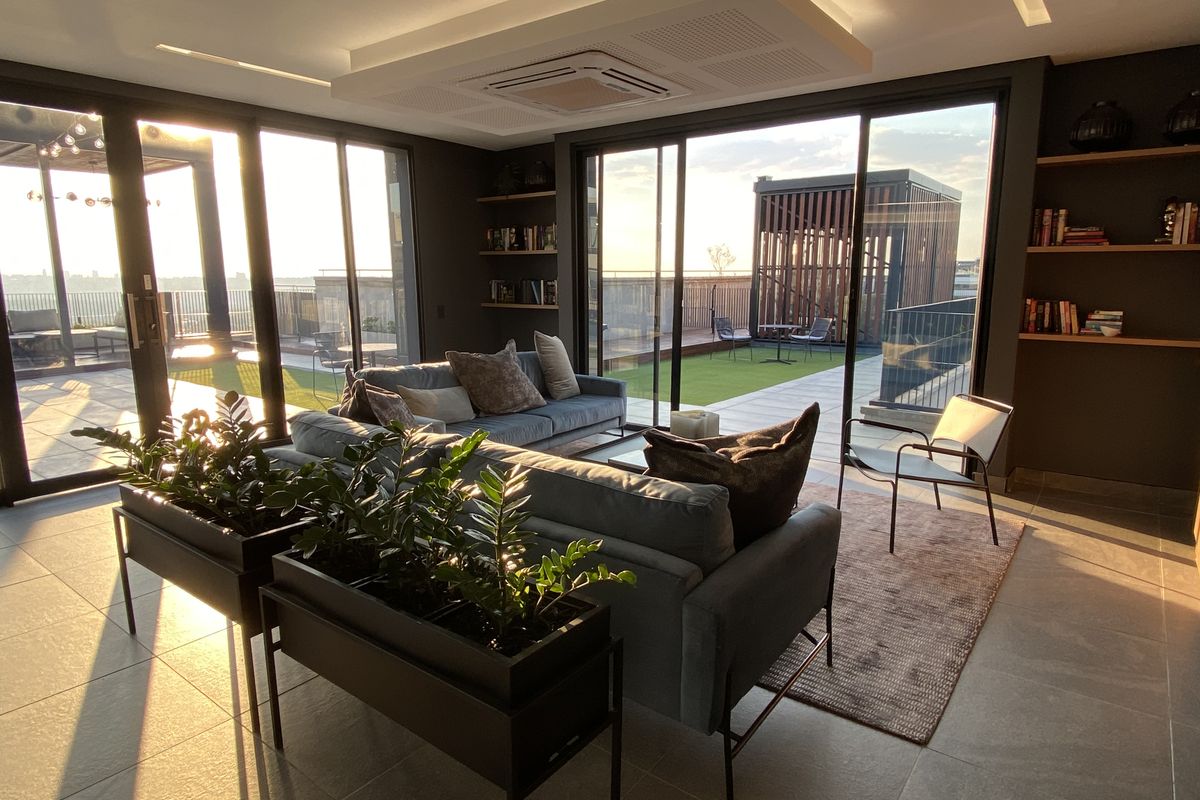 Modern living area featuring large sliding glass doors, recessed ceiling lighting, integrated air conditioning, and built-in shelving, opening onto a spacious outdoor terrace.