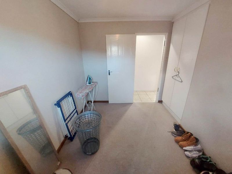 A simple bedroom featuring neutral walls, carpeted flooring, and built-in cupboards, offering a clean and functional space.