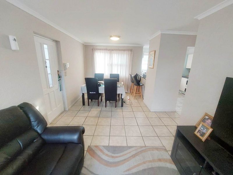 Open-plan living and dining area featuring tiled flooring, coved cornicing, and a breakfast bar connecting to the kitchen space.
