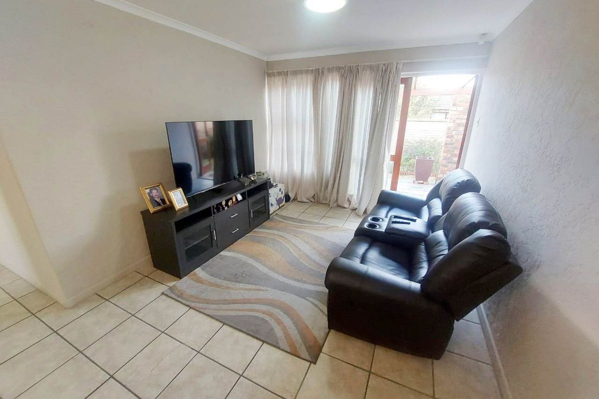 A functional living room featuring tiled flooring, a coved ceiling, and a sliding glass door providing access to the outdoor area.