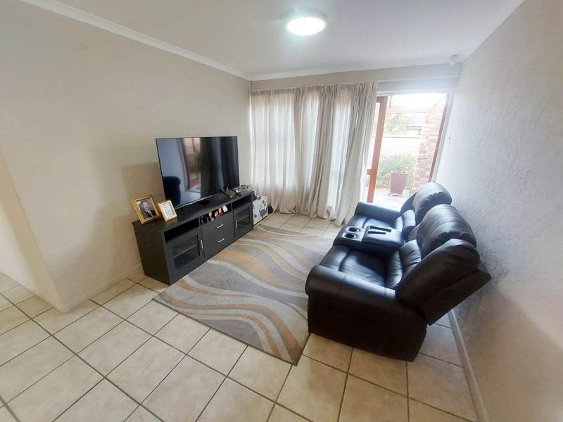 A functional living room featuring tiled flooring, a coved ceiling, and a sliding glass door providing access to the outdoor area.