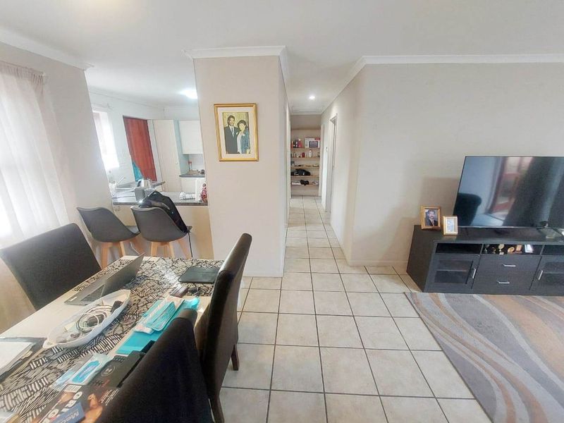 Open-plan living and dining area featuring tiled flooring, a breakfast bar, and a functional kitchen layout with neutral wall finishes.