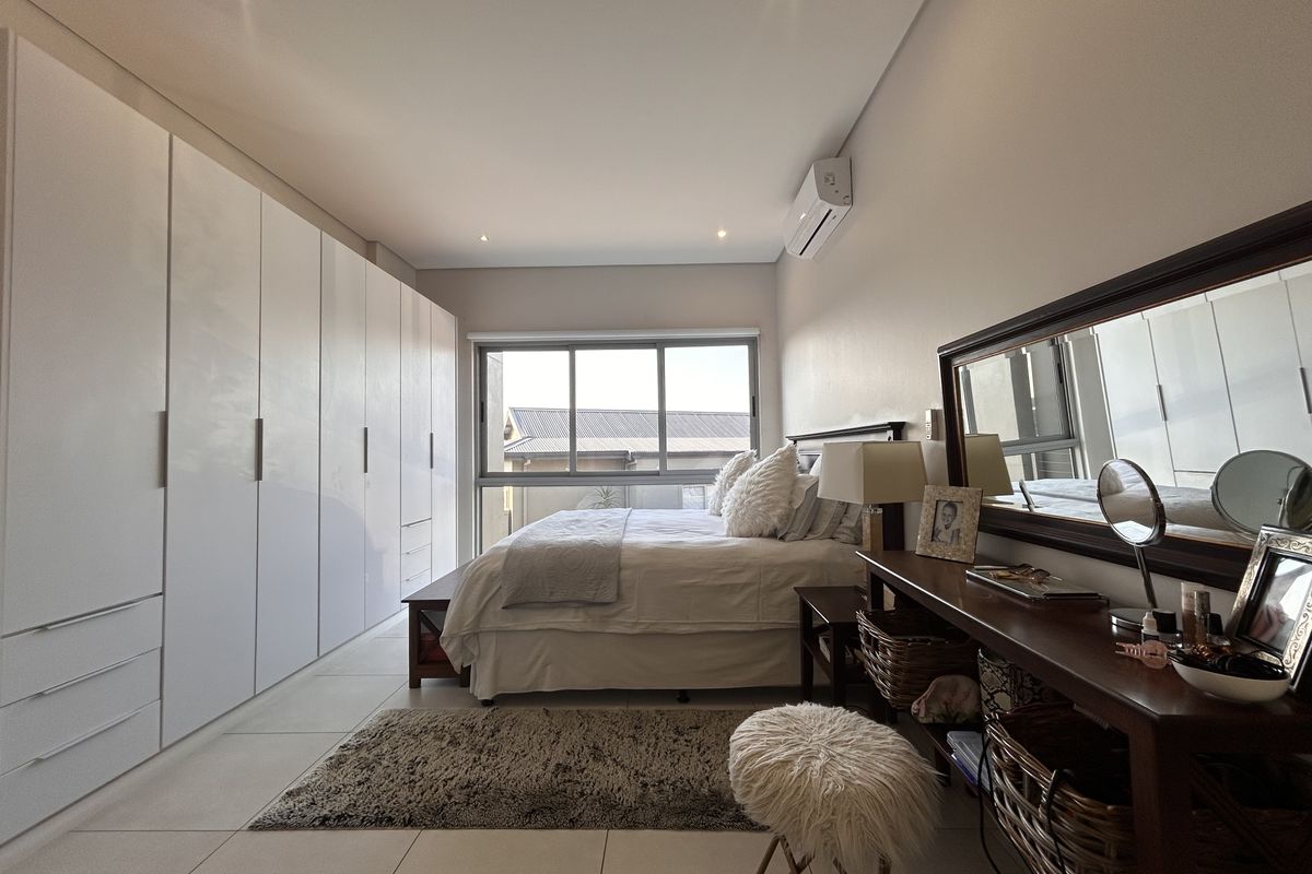 A well-maintained bedroom featuring extensive built-in cabinetry, tiled flooring, and a split-system air conditioner, offering a clean and functional living space.