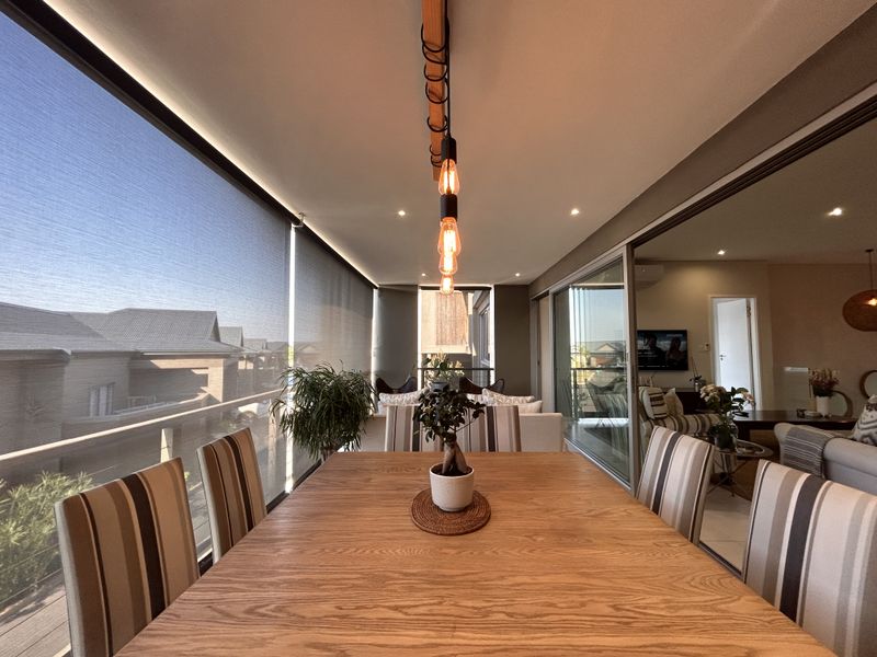 A modern, covered balcony featuring timber decking, recessed lighting, and large sliding glass doors that connect seamlessly to the interior living space.