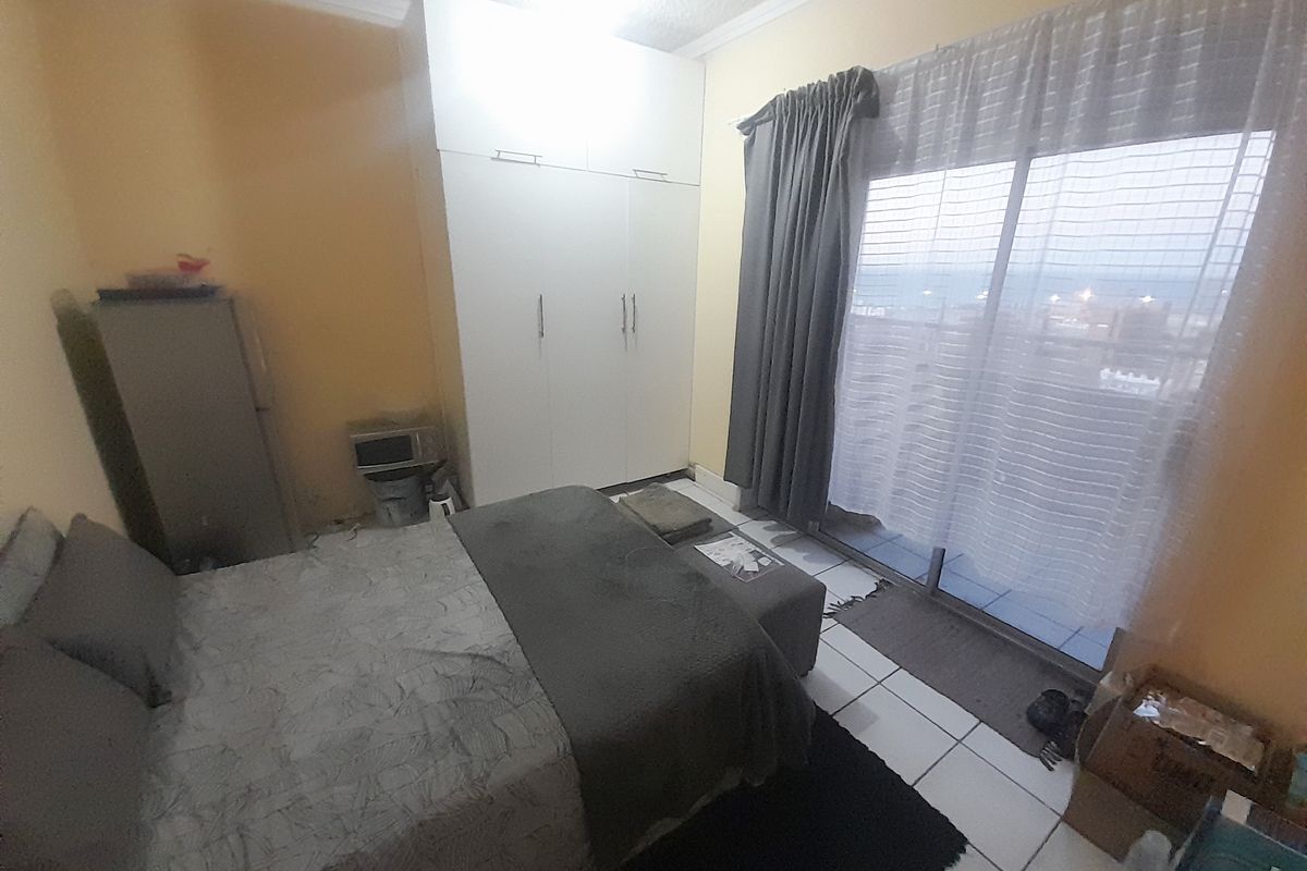 A bedroom featuring built-in wardrobes, tiled flooring, and a sliding glass door providing access to an outdoor balcony area.