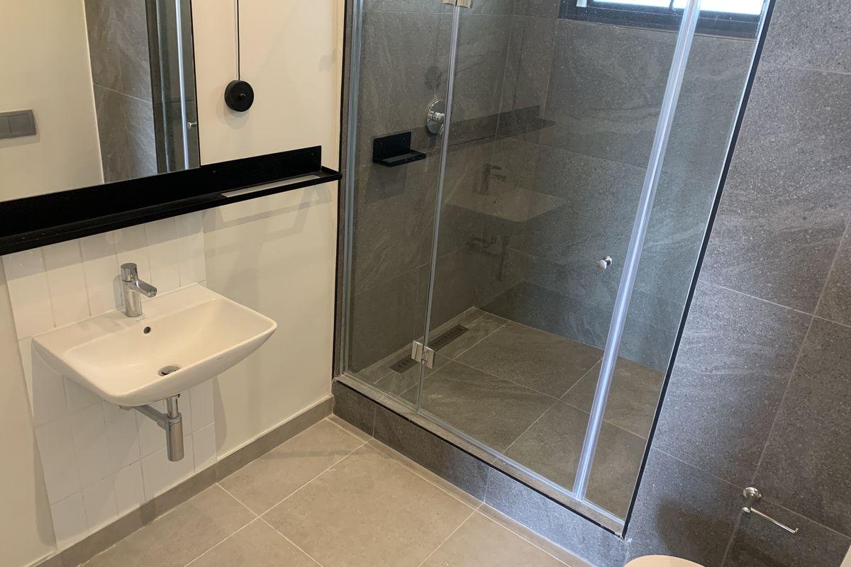 Modern bathroom featuring a wall-mounted basin, glass-enclosed shower with grey tiling, and contemporary fixtures in a clean, minimalist layout.