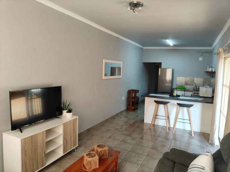 Open plan living and kitchen area featuring tiled flooring, a breakfast bar island, and neutral wall finishes.