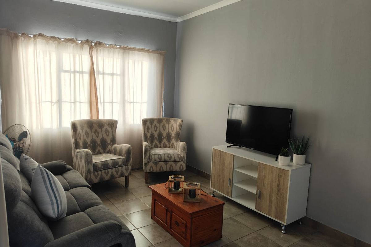 A comfortable living room featuring neutral grey walls and tiled flooring, providing a functional and well-lit space for relaxation.