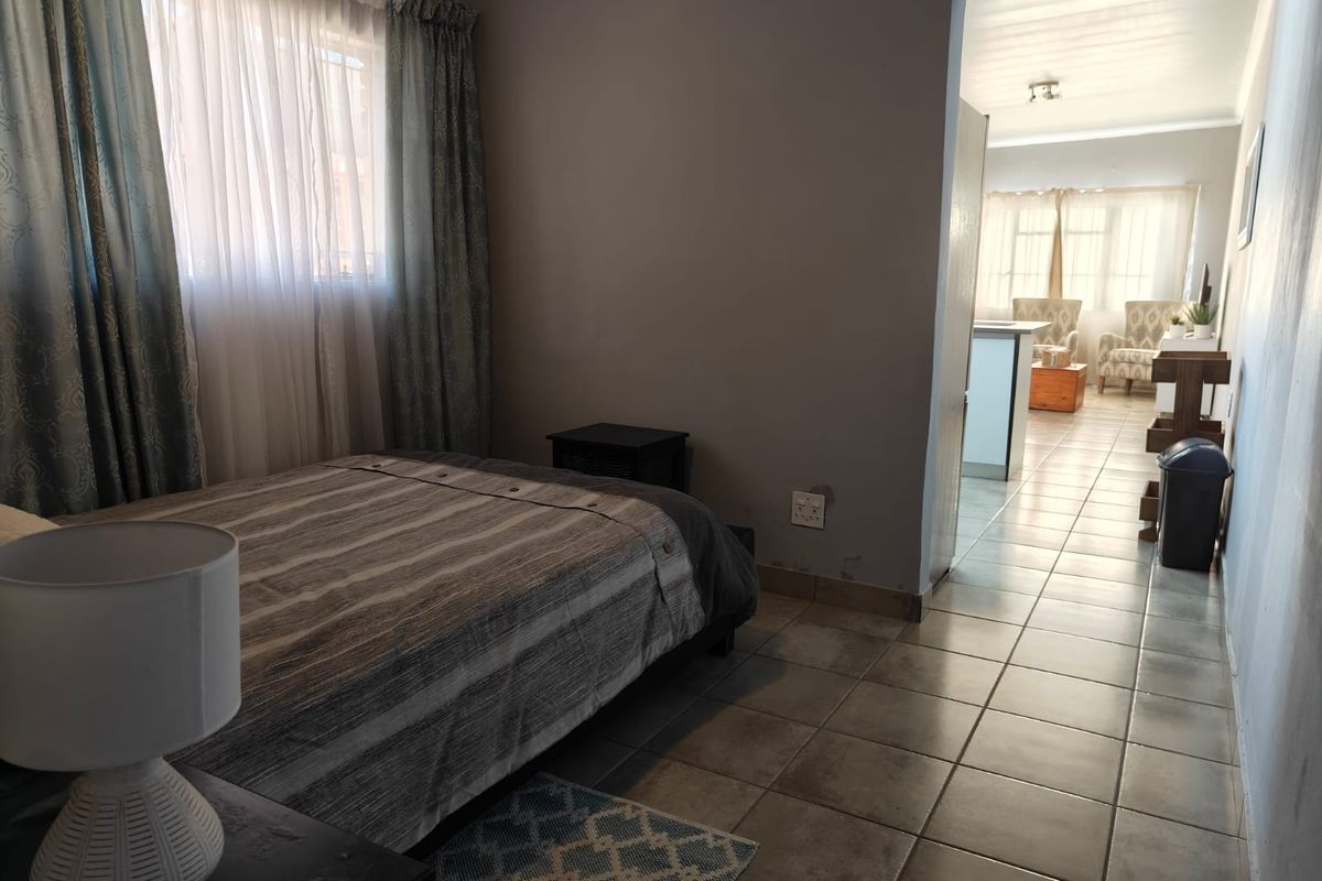 A bedroom featuring tiled flooring and a view through to the adjacent living area.