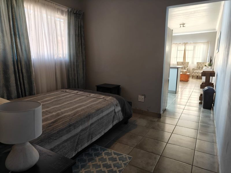 A bedroom featuring tiled flooring and a view through to the adjacent living area.
