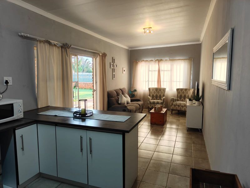 Open-plan living area featuring tiled flooring, a kitchen island with built-in cabinetry, and a sliding glass door providing access to the garden.