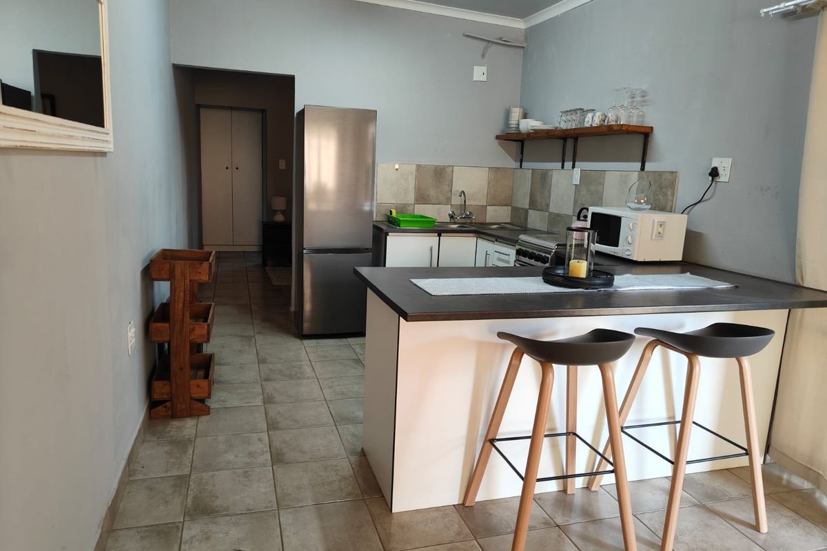 A functional kitchen featuring a breakfast bar, tiled backsplash, and neutral cabinetry, providing a practical layout for daily use.