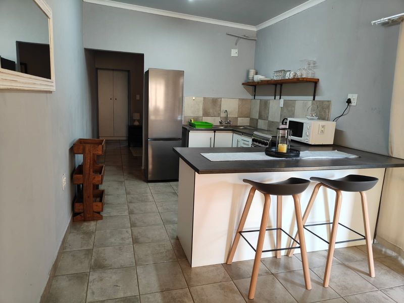A functional kitchen featuring a breakfast bar, tiled backsplash, and neutral cabinetry, providing a practical layout for daily use.