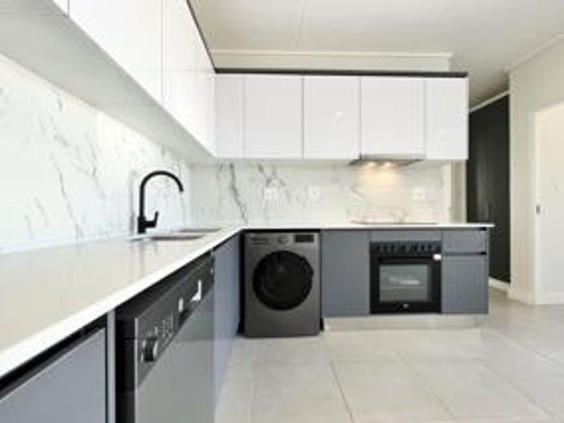 Modern kitchen featuring high-gloss cabinetry, marble-look splashback, quartz countertops, and integrated appliances in a clean, contemporary design.