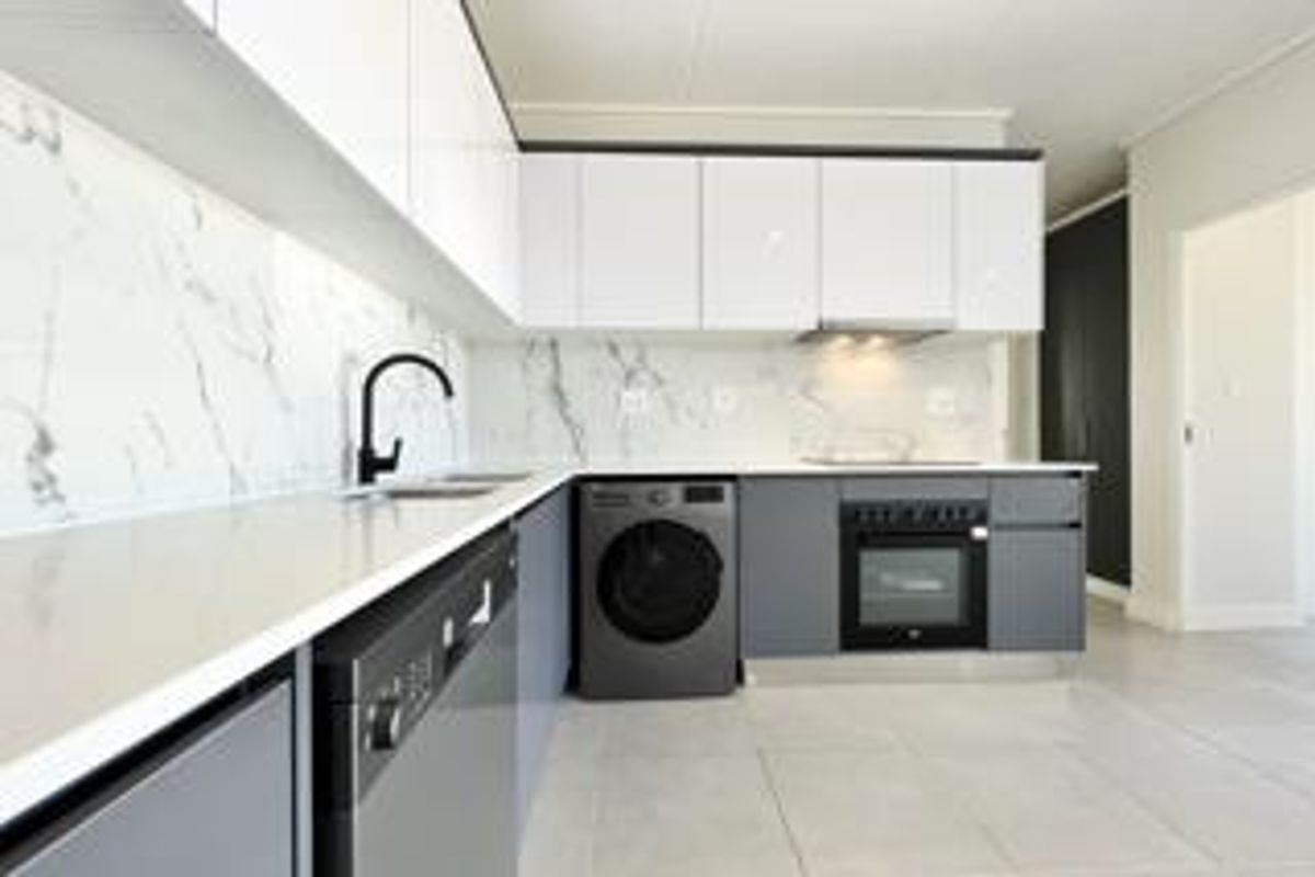 Modern kitchen featuring high-gloss cabinetry, marble-look splashback, quartz countertops, and integrated appliances in a clean, contemporary design.